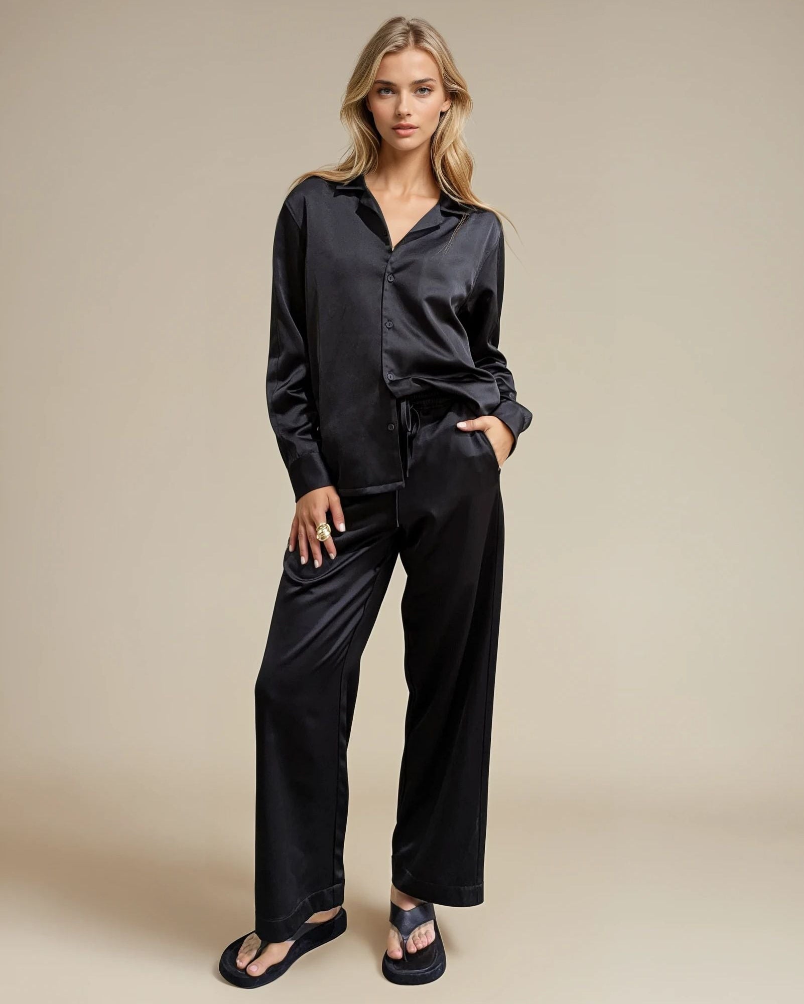 Woman wearing a black satin shirt and pants on a beige background